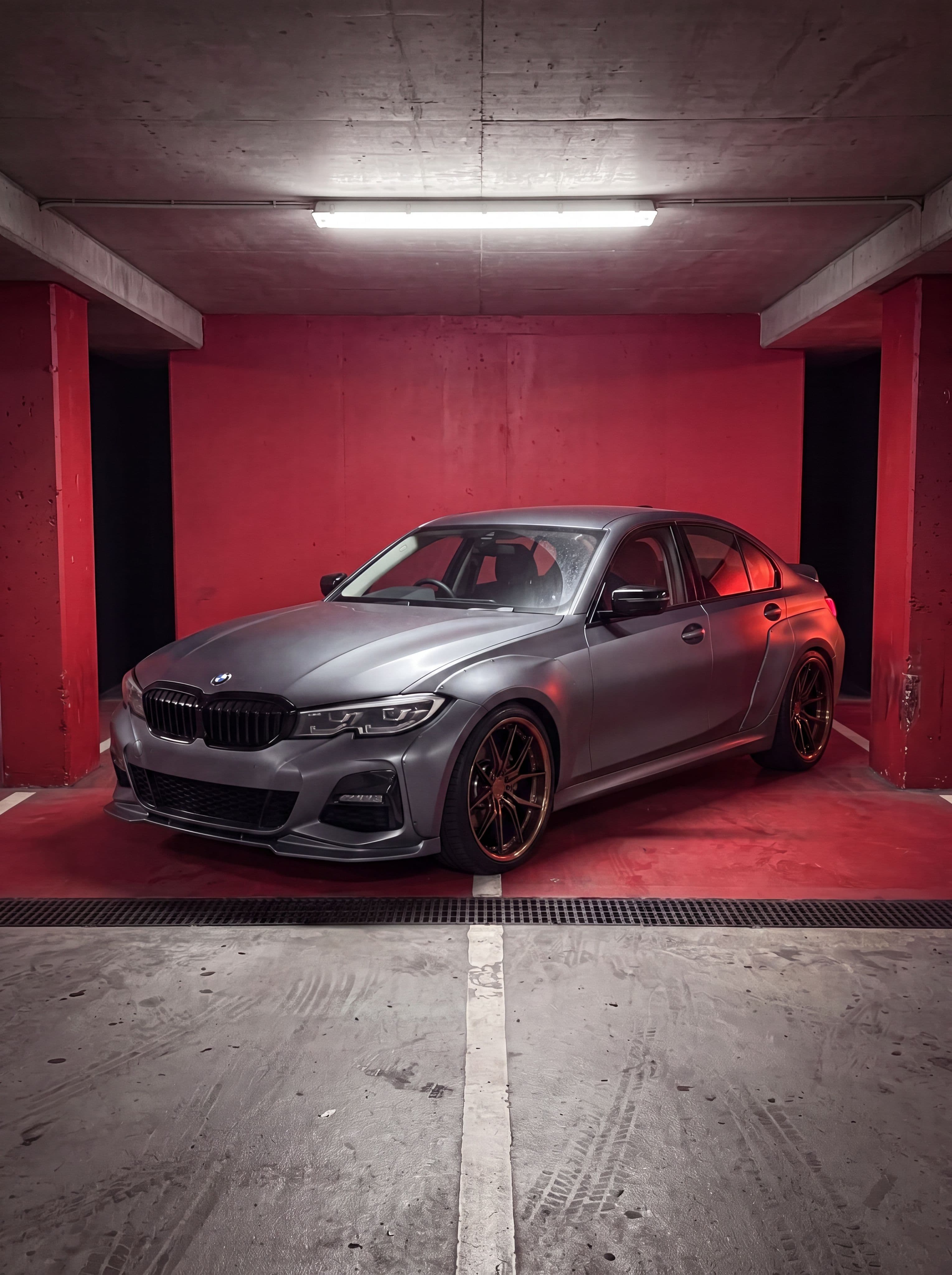 The same car park photo with a front splitter, side skirts, a blacked-out grille, widened arches, bronze forged wheels and a lowered stance rendered onto the car by Car Editor